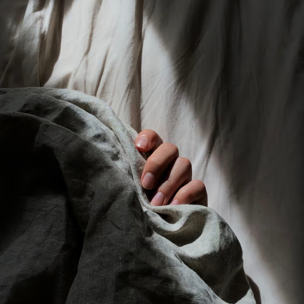 Person resting in bed under gray blankets