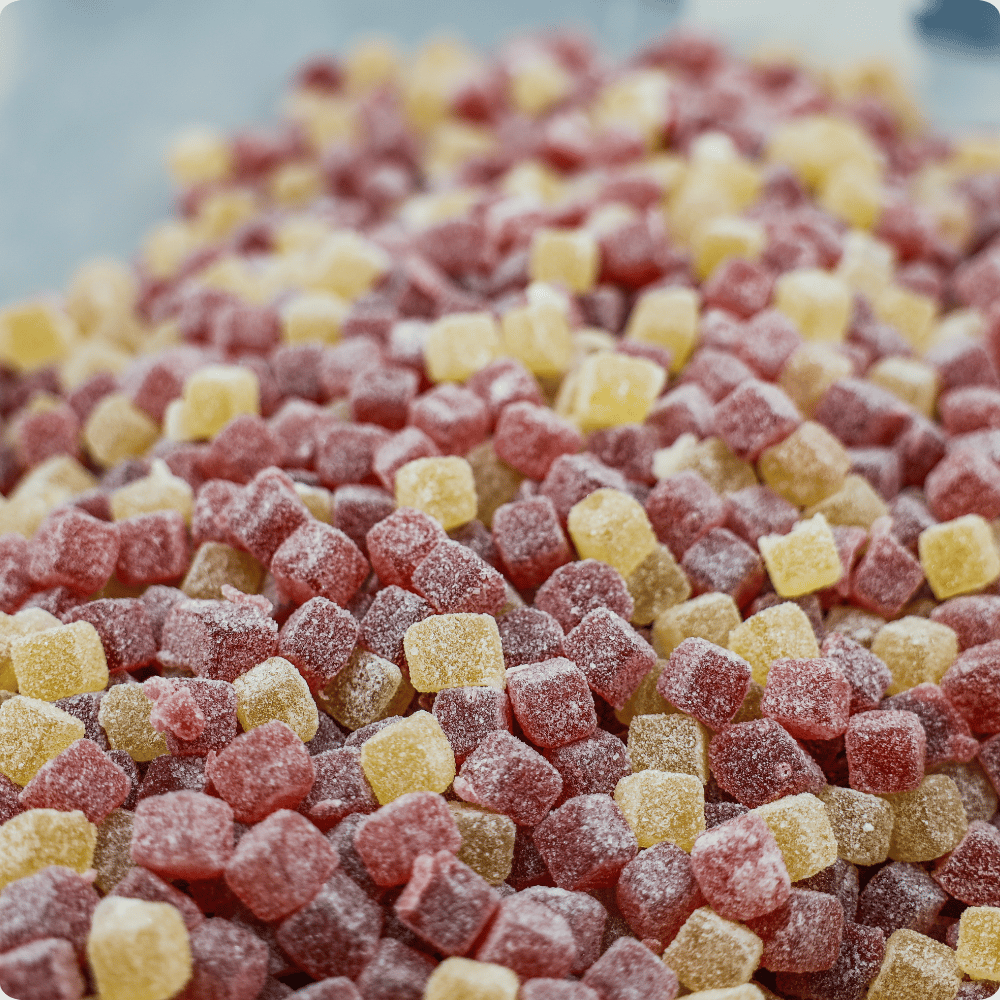 Colorful sugar-coated gummies spread across a white surface