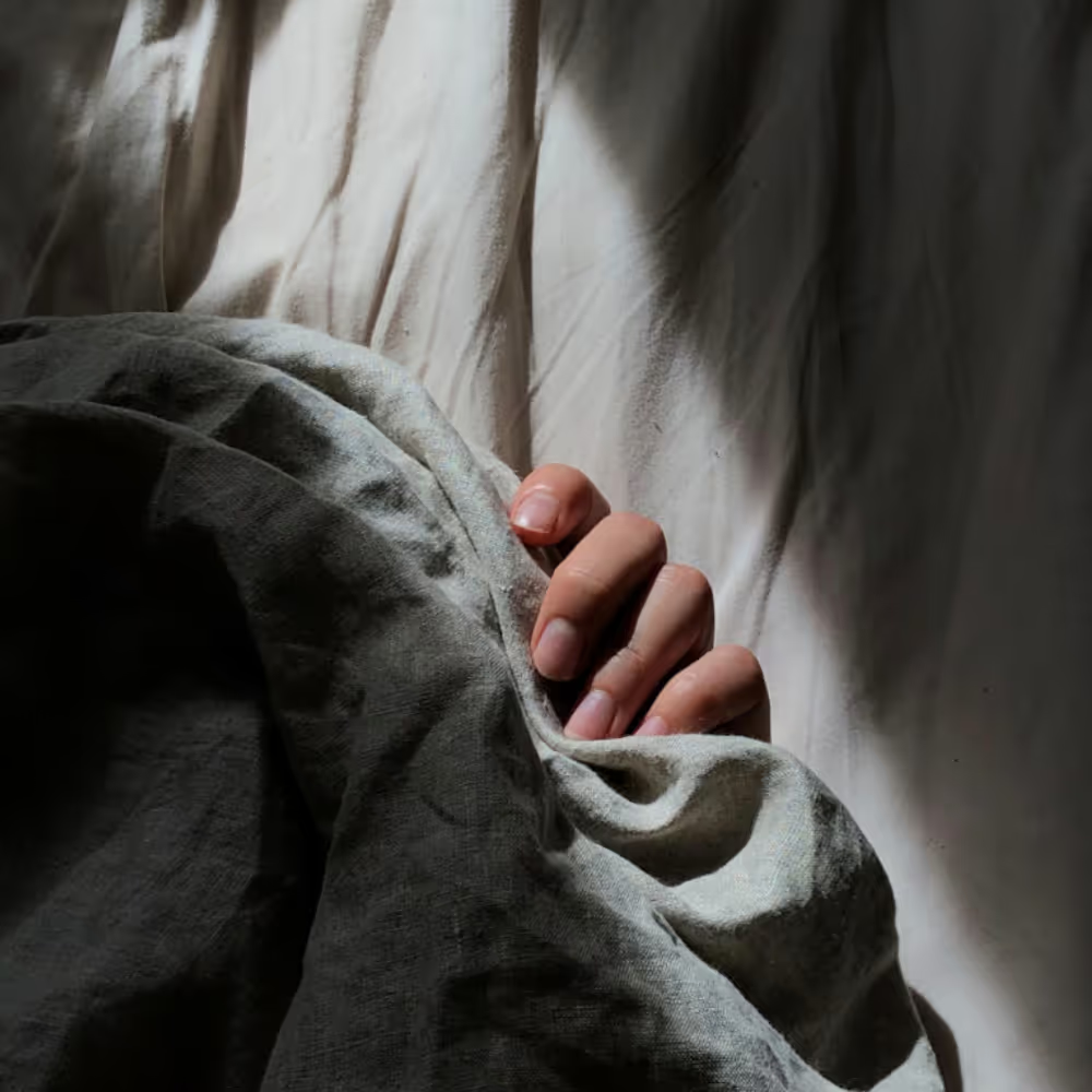Person relaxing in bed under gray blankets