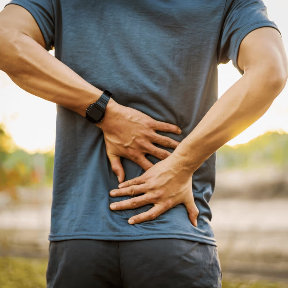 Active man holding his lower back outdoors