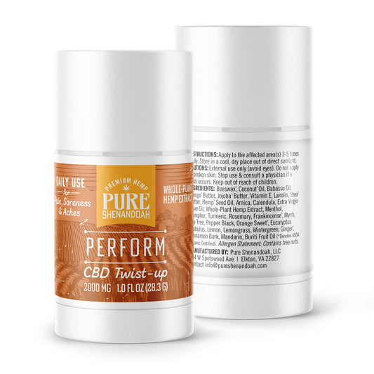 Two Pure Shenandoah Perform CBD Twist-up containers, 2000 mg CBD, 1 oz sticks. One shows the orange wood-grain front label, the other displays back label with ingredients.