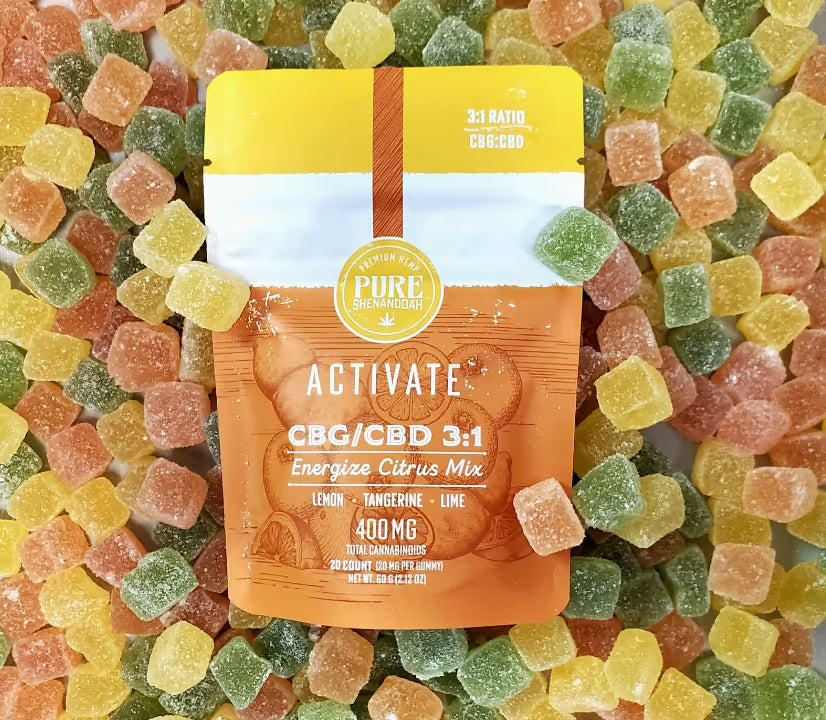 Orange, yellow, and green gummy mix with a package of Pure Shenandoah Activate CBG/CBD 3:1 Energize Citrus Mix gummies in lemon, tangerine, and lime flavors.